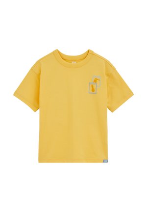 T-shirt jaune à manches courtes et col rond, avec deux petites illustrations encadrées d'un ananas et d'un toucan sur le côté gauche de la poitrine.