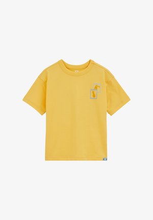 Žuta majica kratkih rukava s okruglim izrezom, ukrašena s dvije male uokvirene ilustracije ananasa i tukana na lijevoj strani prsnog dijela.