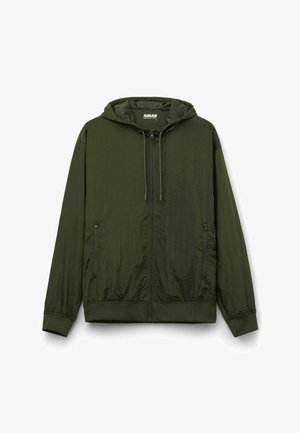 Lehká bunda s kapucí v tmavě zelené barvě. Vyrobena z texturované látky, má celý zip, kapuci na šňůrku a dvě boční kapsy.