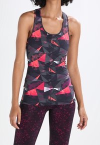 Szary top na ramiączkach z abstrakcyjnymi czerwono-czarnymi geometrycznymi wzorami, w komplecie z bordowymi legginsami o delikatnym, fakturowanym wzorze.