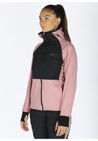 Zip-up jack met een zwart gewatteerd bovenstuk en een roze onderstuk. Heeft een hoge kraag, lange mouwen en duimgaten. Gouden logodetail.