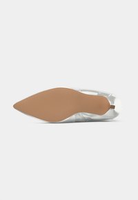 Hõbedased terava ninaotsaga baleriinad vaadatuna põhjast, featuring helepruun tald ja väike kandtab.