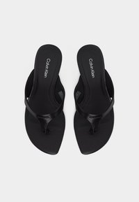 Ζευγάρι μαύρα σανδάλια Calvin Klein τύπου slip-on με λουράκια σχοινί και τετράγωνο σχέδιο μύτης, εκτεθειμένα σε λευκό φόντο.