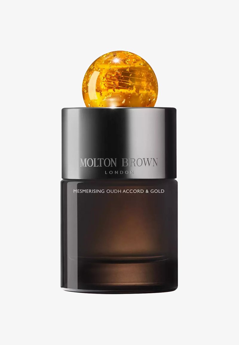 Schwarze Glasflasche mit einem goldenen Globusverschluss. Mit graviertem Text "MOLTON BROWN" und "MESMERISING OUDH ACCORD & GOLD" auf der Oberfläche.