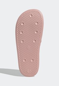Gumowa podeszwa w delikatnym różowym kolorze, z teksturowaną powierzchnią w diamentowy wzór oraz unoszącymi się okrągłymi wypustkami zapewniającymi przyczepność.