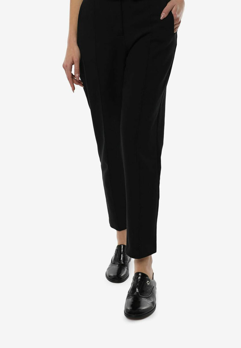 Zwarte op maat gemaakte broeken met een rechte snit, gecombineerd met glanzende zwarte veterschoenen met een gladde afwerking en minimale hardwareaccenten.