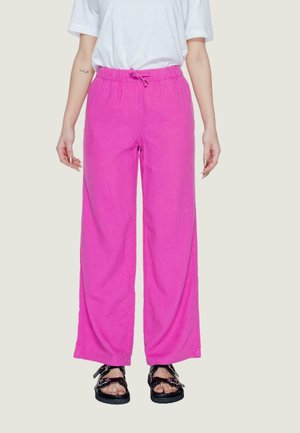 Pantaloni larghi rosa con vita elastica e cordino, realizzati in un tessuto leggero, abbinati a sandali neri con cinturini.