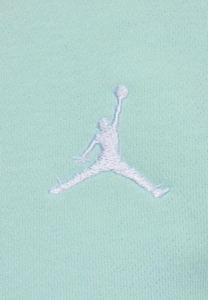 Muntgroene stof met een gestructureerd oppervlak met een wit geborduurd Jumpman-logo. Het ontwerp benadrukt sportieve en casual kleding.