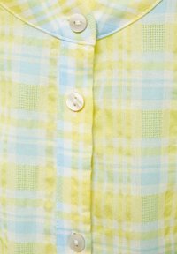 Světle zelená a modrá kostkovaná látka s knoflíkovým zapínáním, která se vyznačuje texturovaným tkaním a malými kostkovanými vzory po celé ploše.