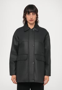 Casaco impermeável preto com gola, fecho frontal de pressão, dois bolsos na frente e um acabamento liso e mate.