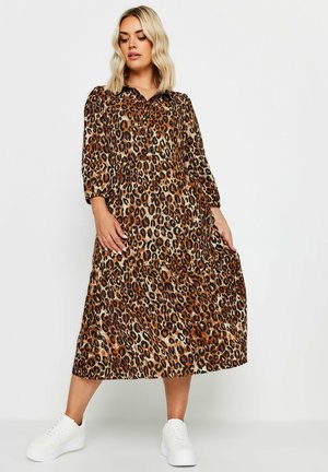 Leopardenprint middellange jurk met een kraag, 3/4 mouwen en een geplisseerde rok, gecombineerd met witte sneakers. De stof heeft een gladde textuur.