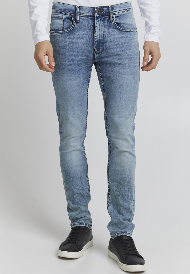 Ljust blå denimjeans med slim fit, med fem fickor, kontrasterande sömmar och blekta områden för en sliten look. Burit med svarta sneakers.