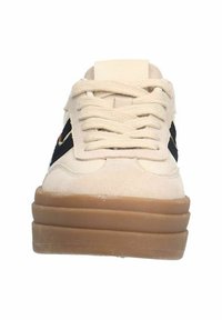 Cream-colored sneaker with black accents, textured suede upper, flat laces, and a brown rubber sole, featuring a cushioned platform.