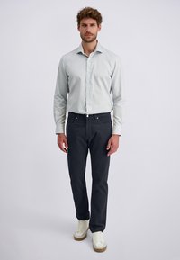 Light gray button-up shirt, black jeans, and white sneakers. The shirt features a collar and a fitted silhouette. Simple design with no patterns.