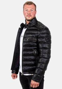 Giacca puffer nera in pelle, con chiusura a zip, design trapuntato, tasche laterali e sul petto, e colletto alto con finitura testurizzata.