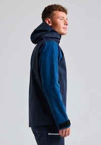 Giacca impermeabile blu e blu con cappuccio. Caratteristiche includono una tasca frontale, polsini regolabili e una texture liscia.