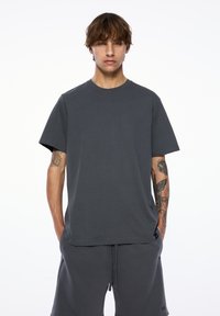 Graues Kurzarm-T-Shirt aus Baumwolle mit Rundhalsausschnitt und lässiger Passform, das dezente Nähte aufweist und keine sichtbaren Muster oder Akzente hat.