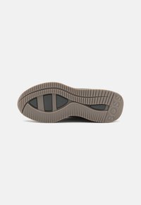 Semelle de chaussure avec motif de bande de roulement rainuré, comportant trois sections en caoutchouc noir et le mot "BOSS" embossé près du talon.