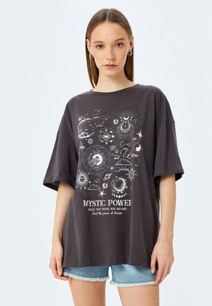 Donkergrijze oversized t-shirt met korte mouwen, voorzien van witte hemelse graphics en de tekst "MYSTIC POWER" gedrukt op de voorkant.