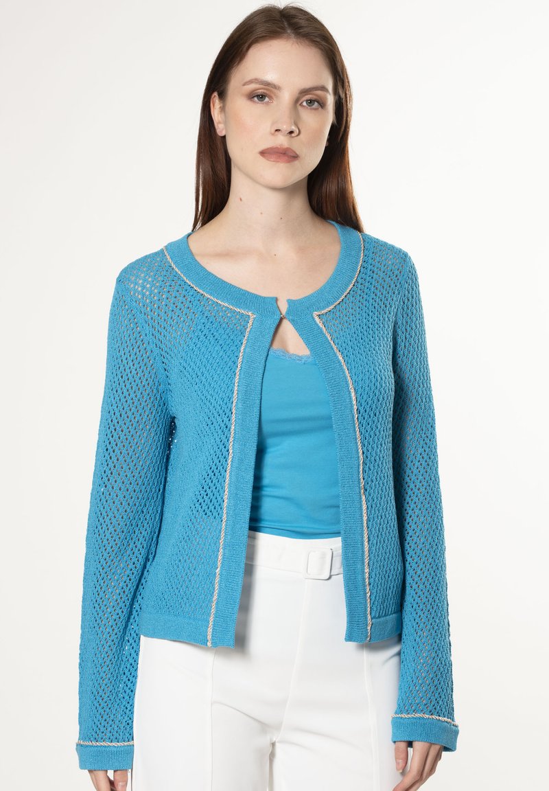 Hellblaues Strickcardigan mit offenem Muster, rundem Halsausschnitt und Schlüsselaugen-Detail. Verfügt über einen kontrastierenden Saum und eine weiche Textur.