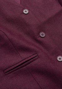 Bordo blejzer s teksturiranom tkaninom, dvostrukim kopčanjem, dva dugmeta i bočnim džepom s ravnim otvaranjem.