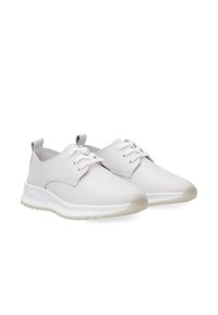 White leather sneakers with a smooth finish, featuring a rounded toe, lace-up design, and contrasting rubber sole with a slight transparency.