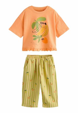 Detský dvojdielny outfit s broskyňovým tričkom s krátkym rukávom s kreslenými banánmi a pomarančom a zelenými pásikavými nohavicami s motívmi banánov a ananásov.