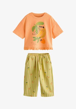 Detský dvojdielny outfit s broskyňovým tričkom s krátkym rukávom s kreslenými banánmi a pomarančom a zelenými pásikavými nohavicami s motívmi banánov a ananásov.