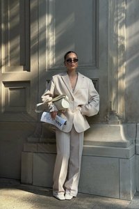 Hellbeige oversized Blazer und passende weit geschnittene Hose, kombiniert mit quadratigen Absatzschuhen. Ergänzt durch eine helle Handtasche und Sonnenbrille.