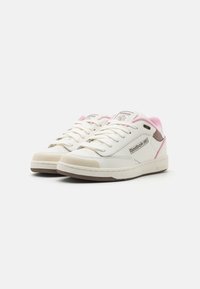 Sneaker Reebok bianchi e rosa con tomaia in pelle liscia, punta tonda, perforazioni per la traspirabilità e suola in gomma testurizzata.