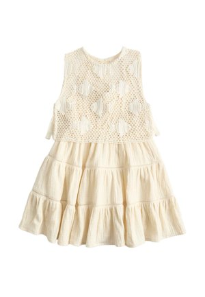 Vestido sin mangas crema con falda de volantes texturizados y cuerpo de encaje de crochet con patrones de conchas, cierres de lazo en los costados.