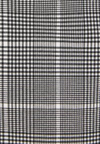 Czarnobiały materiał w kratę typu psygoń z teksturowanym splotem. Charakteryzuje się na przemian małymi i dużymi kratkami, tworząc wyrazisty wzór.