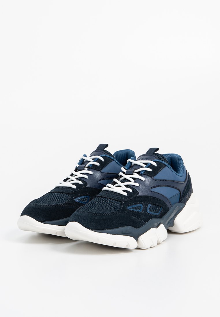 Ein Paar marineblaue und schwarze Sneakers mit weißen Sohlen und Schnürsenkeln, die auf einem weißen Hintergrund mit Mesh- und Wildlederdetails versehen sind.