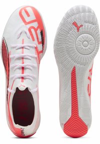 Baskets blanches de sport avec des accents roses, tige en maille, et semelles texturées dotées d'un motif de grip, détail de logo et lacets ajustables.