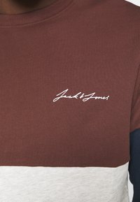 Brun och grå färgblockerad tröja med rund halsringning. Har vit skriptlogotyp "Jack & Jones" på bröstet. Tillverkad av bomull.