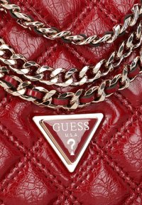 Rote, gesteppten Kunstlederhandtasche mit einem dreieckigen Logo-Emblem. Doppelter Goldkettenriemen mit schwarzen Akzenten, die eine strukturierte Oberfläche betonen.