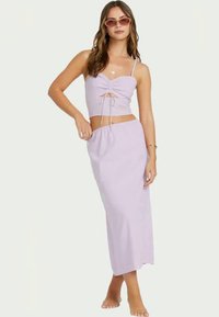 Lilac two-piece outfit with a cropped top featuring a front tie detail and a long skirt. The fabric appears lightweight and smooth.