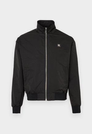 Veste noire zippée avec col montant, poignets et ourlet côtelés, poches latérales et un petit patch logo sur la poitrine gauche.