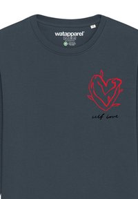 T-shirt à manches longues bleu foncé avec un design de cœur rouge et le texte "self love" en noir. Fabriqué en tissu de coton doux et texturé.