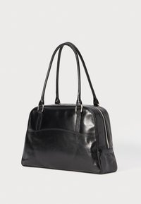 Black leather handbag with two long handles and a silver zipper on the side, photographed against a white background.