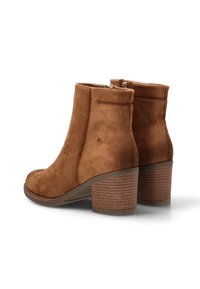 Botas de ante marrón hasta el tobillo con puntera redondeada, cremallera lateral y un tacón apilado y texturizado. Presenta una textura suave y lisa.