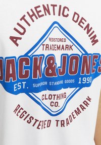 Witte t-shirt met een rood en blauw grafisch ontwerp met "JACK & JONES", "AUTHENTIC DENIM" en "CLOTHING CO." in verschillende lettertypen en groottes.