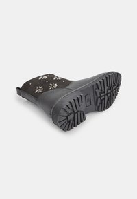 Stivale nero con una base in pelle testurizzata e parte superiore in morbido suede. Presenta ricami floreali e una suola in gomma resistente con un battistrada decorato.