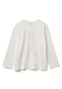 Bílá dlouhá bavlněná tričko s kulatým výstřihem. Materiál je hladký, s volným střihem a bočními rozparky u spodního lemu.