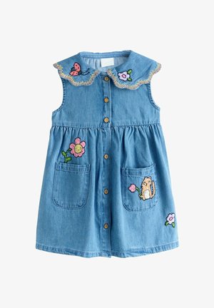 Sininen farkkumekko, jossa on aaltoileva kaulus, kirjailtuja kukkia ja kissa taskuissa, varustettuna puisilla napeilla ja poimutetulla vyötäröllä.