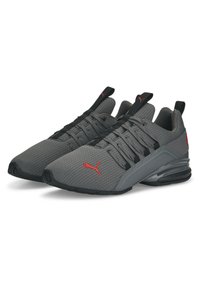 Baskets de sport grises avec une tige en mesh, des accents noirs et un logo rouge. Elles disposent d'une semelle rembourrée et d'un design épuré avec des lacets.