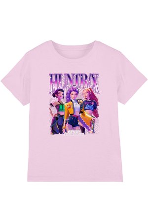 Light pink shirt with bold graphic of three animated K-pop style female characters under "HUNTRX" text, with "K-POP DEMON HUNTERS" below.