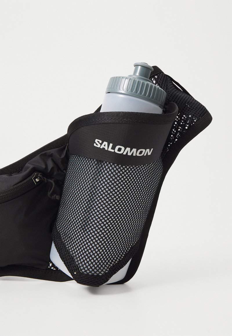 Black mesh water bottle holder with grey bottle, featuring a twist cap and the logo "SALOMON." Compact design, suitable for hydration on the go.