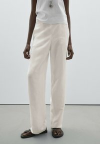 Wide-leg trousers in soft white fabric, featuring a smooth texture and simple design. Paired with black flip-flops and a light top.