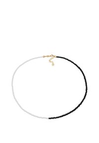 Collier de perles avec des perles blanches et noires alternées, doté d'un fermoir doré et d'une chaîne ajustable pour varier la taille.